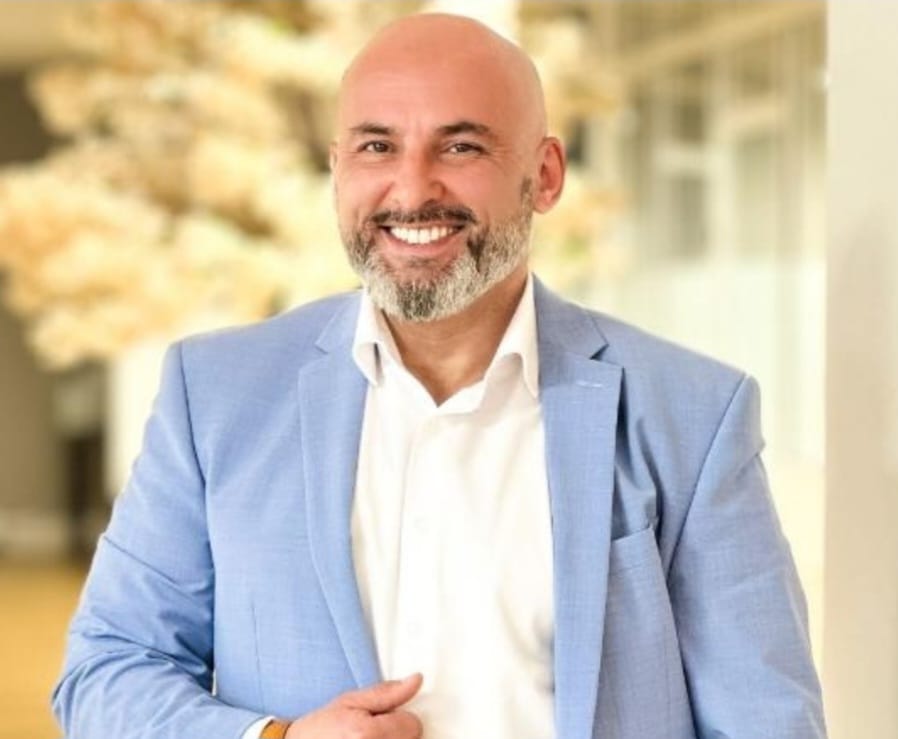 Businessman in blue suit smiling indoors.